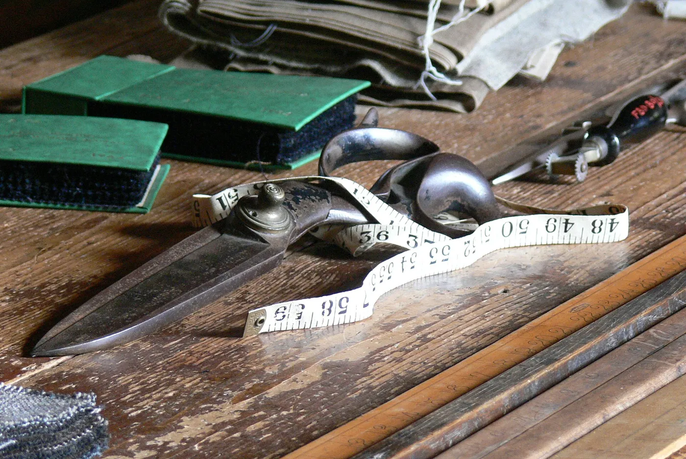 Schneiderschere, Maßband und Werkzeuge auf einem Holztisch